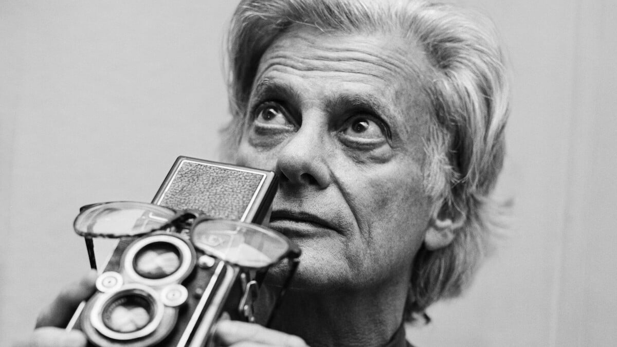 Richard Avedon holding a Rolleiflex camera in a black and white portrait