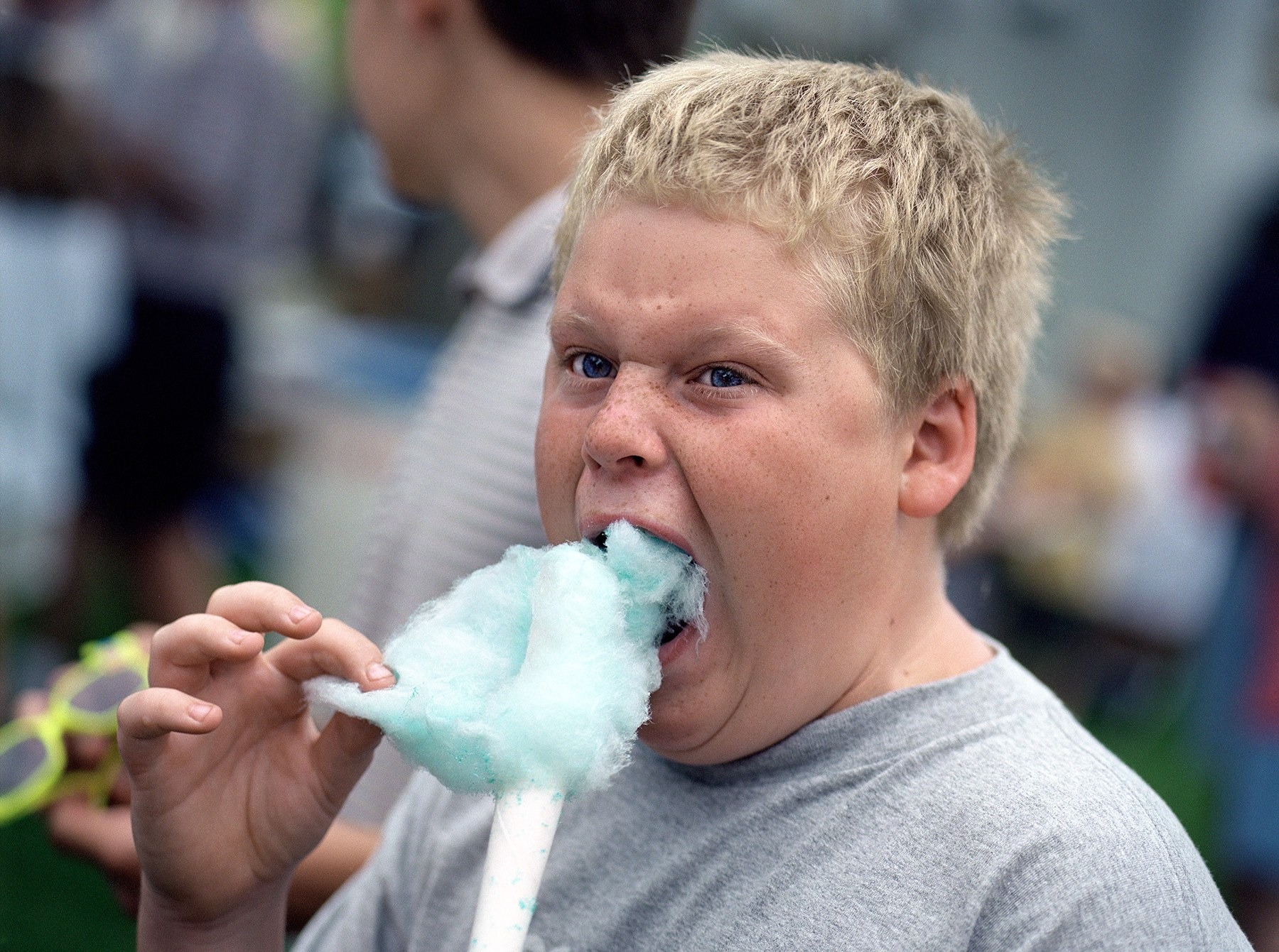 A boy eating blue cotton candy at a Fourth of July celebration in Garnavillo, Iowa, photographed by Stephen Wilkes.